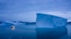 Sebuah kapal yang berlayar pada malam hari, bergerak melewati bongkahan es besar di wilayah timur Greenland pada 15 Agustus 2019. (Foto: AP/Felipe Dana)
