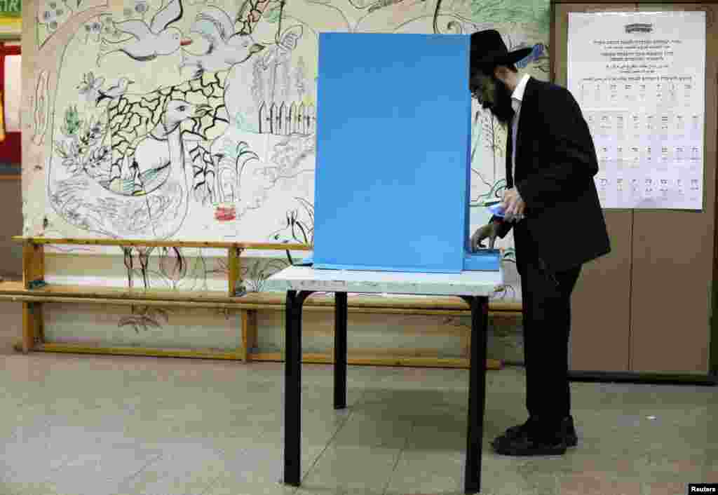 An ultra-Orthodox Jewish man stands near a booth at a polling station in the West Bank Jewish settlement of Kochav Ya'acov, north of Jerusalem, January 22, 2013.