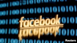 FILE - A 3-D printed Facebook logo is seen in front of displayed binary code in this illustration picture.