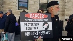 South Carolina coastal resident Phil Frandino holds a sign at the Charleston announcement of a lawsuit against the Trump administration to stop future seismic airgun testing in the Atlantic Ocean, in Charleston, S.C., Dec. 11, 2018.