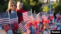 FILE - A couple looks over 58 wooden crosses, with the names and photos of the October 1 mass shooting victims, in the median of Las Vegas Boulevard South near the "Welcome to Las Vegas" sign in Las Vegas, Nevada, Oct. 9, 2017.