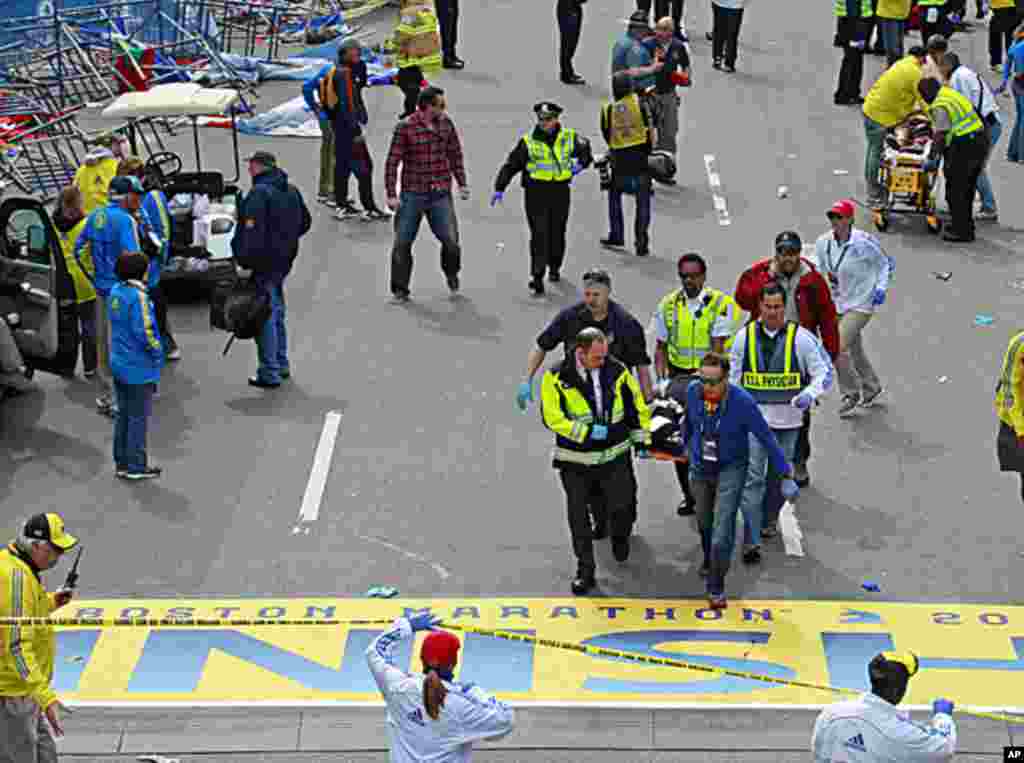 Medical workers transport the injured across the finish line during the 2013 Boston Marathon following an explosion, April 15, 2013.