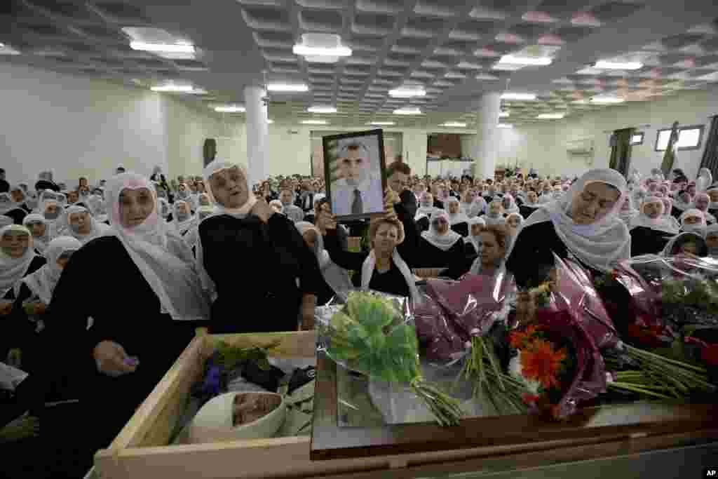 The wife of Israeli Chief Inspector Border Police officer Jedan Assad holds his photograph as she mourns during his funeral procession, in the Druse village of Beit Jann on Mt. Meron, Galilee, Israel, Nov. 6, 2014.