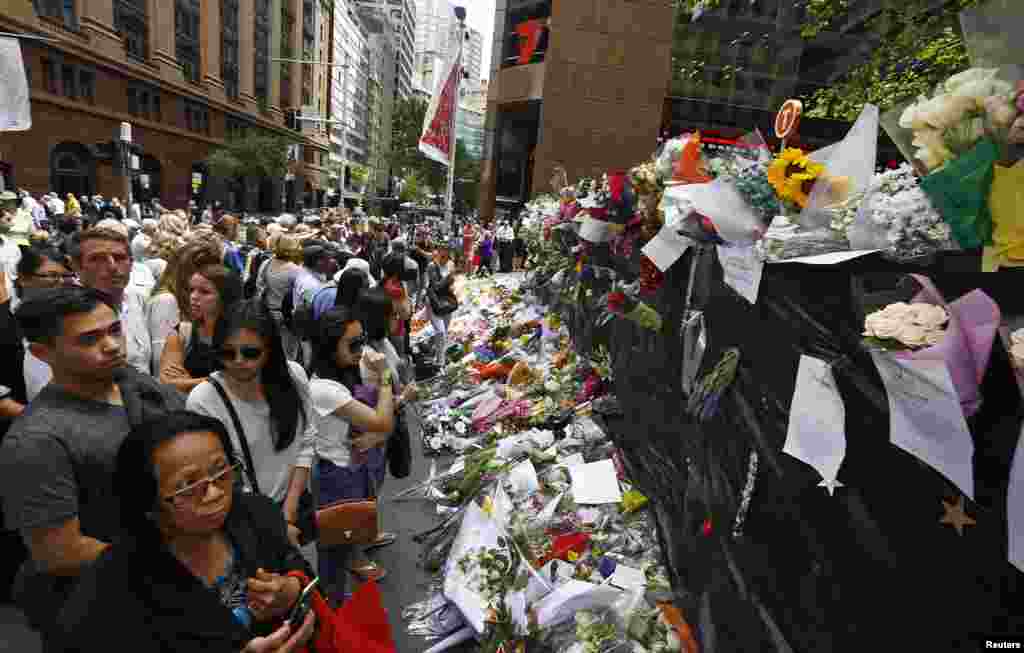 Masyarakat di situs memorial dekat kafe Lindt di distrik bisnis Sydney, Australia, tempat warga terus memberikan bunga tanda penghormatan, Kamis (18/12). 