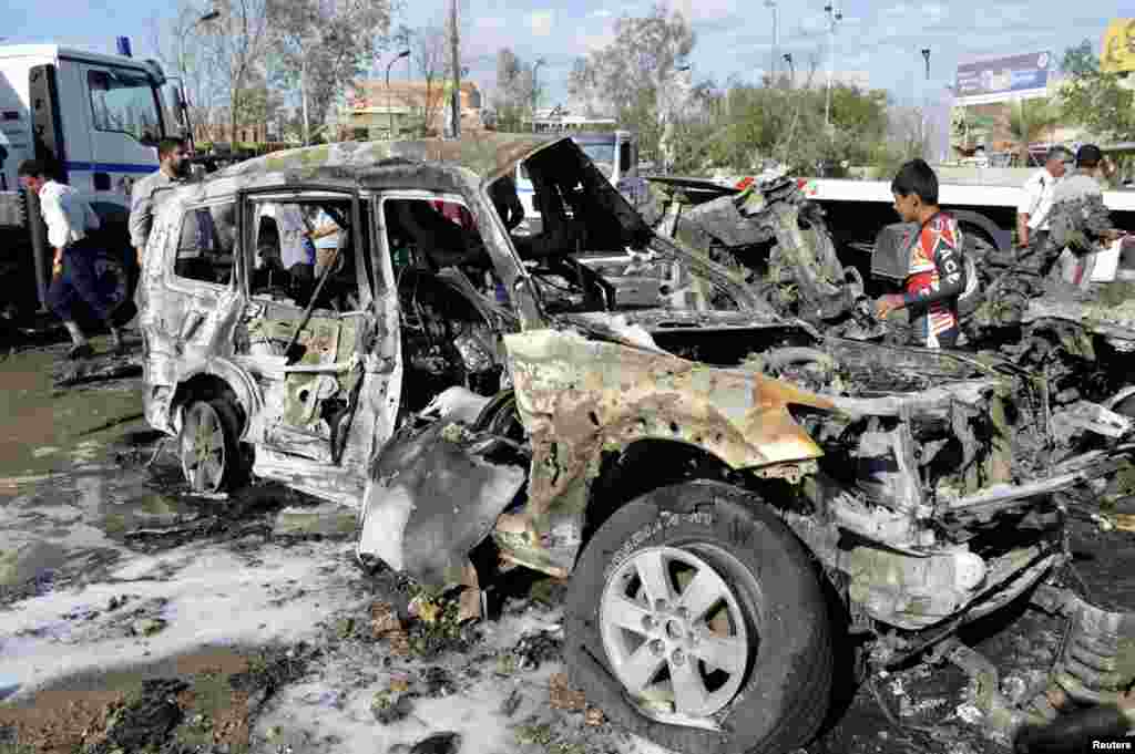 Iraqi security forces and civilians gather at the site of a car bomb, after a series of bombs targeting restaurants across Baghdad killed at least 21 people. Many of the recent attacks have been claimed by Islamic State militants who have overrun large parts of Iraq and neighboring Syria, Oct. 21, 2014. 
