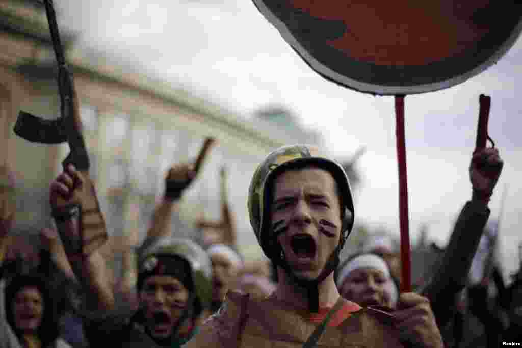 Para mahaiswa Bulgaria dengan mengenakan seragam militer palsu meneriakkan slogan anti-pemerintah selama demonstrasi di depan Universitas Sofia, di ibukota Bulgaria, untuk memrotes korupsi yang merajalela, pengangguran dan rendahnya upah buruh.