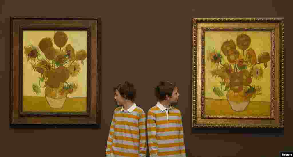 Si Kembar Edgar (kiri) dan Gabriel berpose untuk para juru foto di antara dua lukisan Vincent van Gogh, Bunga Matahari 1888 (kiri) dan Bunga Matahari 1889 di Galeri Nasional di London. Kedua lukisan itu &quot;dipertemukan&quot; di London untuk pertama kalinya dalam 65 tahun dan akan dipamerkan selama tiga bulan dari tanggal 25 Januari 2014. 