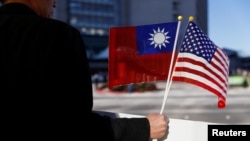 Seorang demonstran memegang bendera Taiwan dan Amerika Serikat untuk mendukung Presiden Taiwan Tsai Ing-wen saat transit di Burlingame, California, 14 Januari 2017, seusai melakukan kunjungan ke Amerika Latin. (Foto: dok).