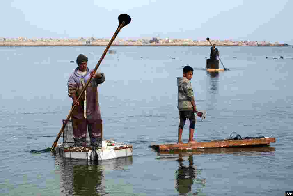 Seorang pria Palestina menggunakan pintu kulkas sebagai perahu dayung darurat untuk menangkap ikan di pelabuhan Kota Gaza. (AFP) 