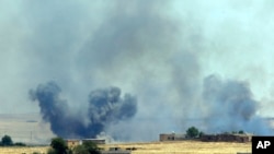 Asap mengepul akibat serangan udara koalisi pimpinan AS di pinggiran kota Tal Abyad yang menjadi kubu ISIS di Suriah, dekat perbatasan Turki, Minggu (14/6).