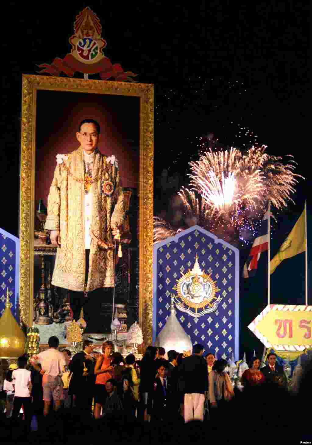 រូបព្រះមហាក្សត្រថៃព្រះបាទ Bhumidol Adulyadej (ខាងឆ្វេង) ដាក់នៅលើឆាកមួយ ស្របពេលមានការបាញ់កាំជ្រួច នៅក្រុងបាងកក កាលពីថ្ងៃទី០៥ ខែធ្នូ ឆ្នាំ១៩៩៩ ក្នុងការអបអរសាទរពិធីបុណ្យចម្រើនព្រះជន្ម ៧២ ព្រះវស្សា។ 