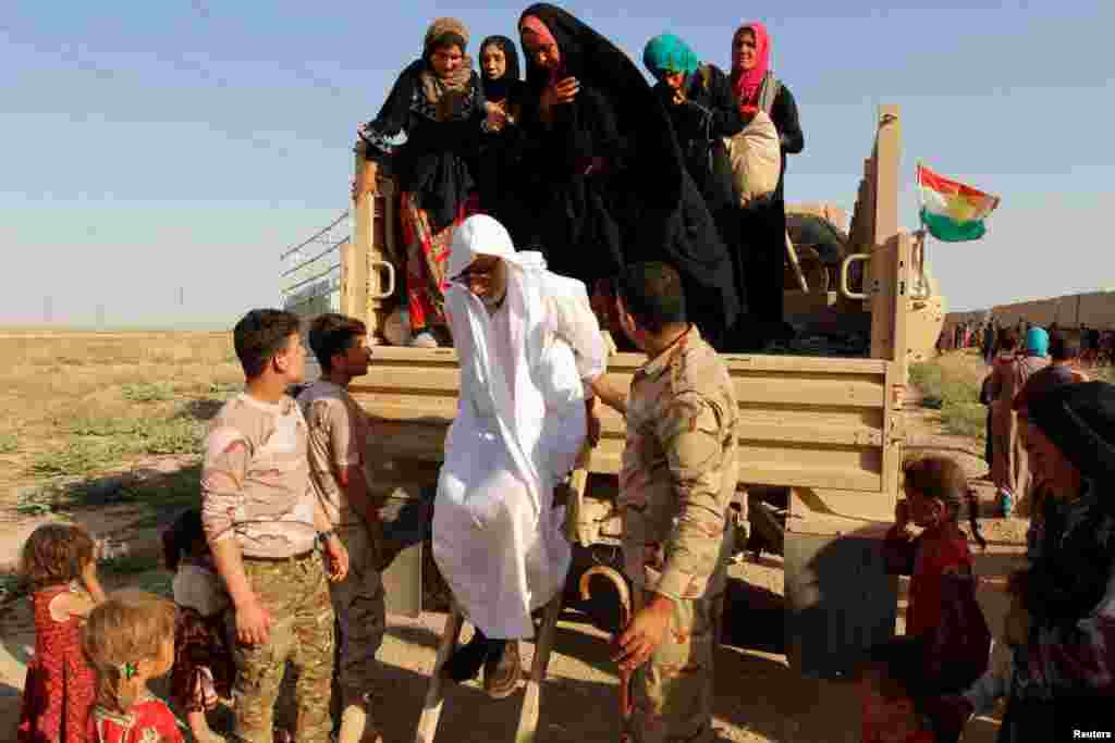 Kurdish Peshmerga forces help people from Sunni Muslims, who fled the Islamic State&#39;s strongholds of Hawija, as they arrive on the outskirts of Kirkuk, Iraq.