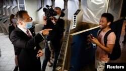 New York Governor Andrew Cuomo greets a subway rider after riding a #7 subway train in Manhattan on the first day of New York City's phase one reopening during the outbreak of the coronavirus disease (COVID-19) in New York City, June 8, 2020.