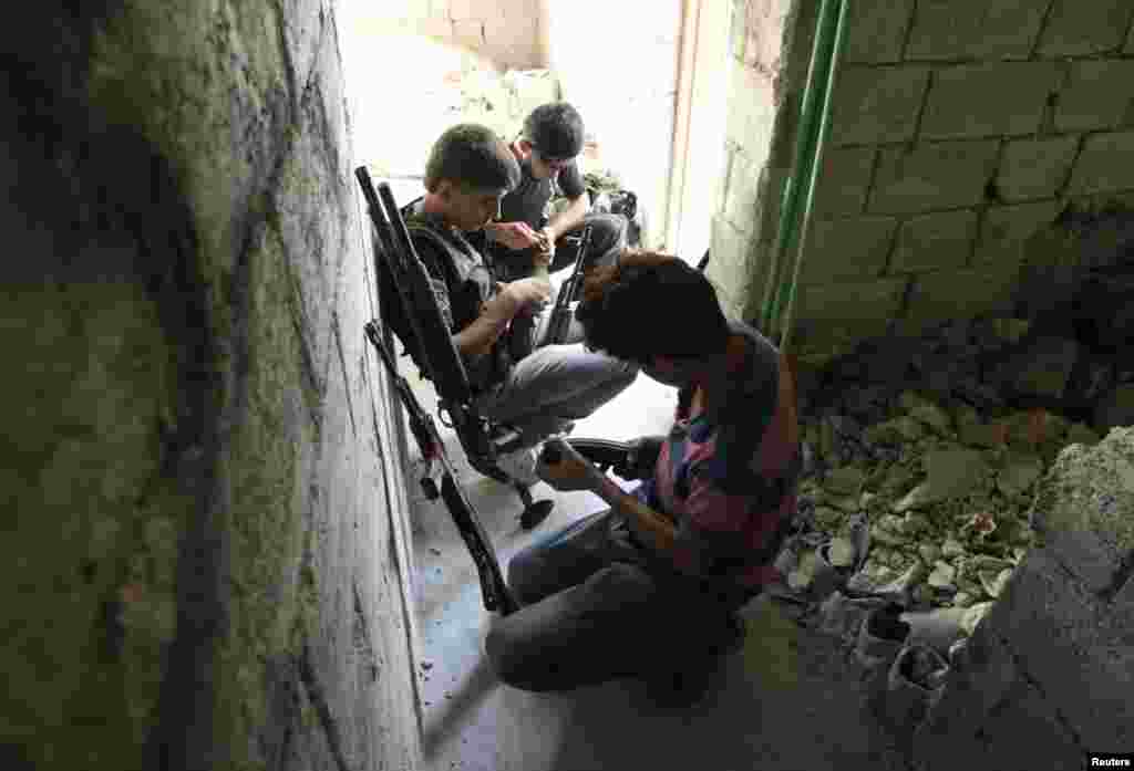 Free Syrian Army fighters check their weapons as they take positions during what they say is an offensive against forces loyal to Syria's President Bashar al-Assad.