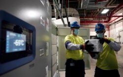 The temperature on a freezer reads -69°C as workers move boxes containing the Pfizer-BioNTech COVID-19 vaccines to be shipped at the Pfizer Global Supply Kalamazoo manufacturing plant in Portage, Michigan.