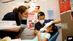 FILE - UT Health Dental School student volunteers provide a free dental screening on a child at Fiesta Mart in Houston, June 13, 2015.