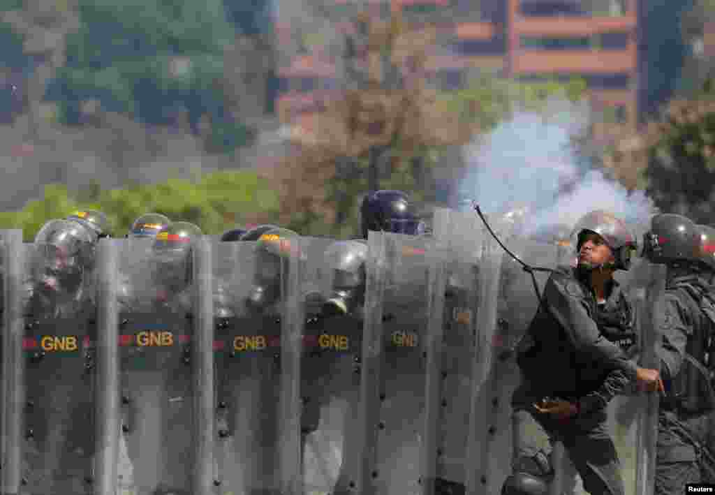 A member of the National Guard throws an object toward opposition supporters during a rally against the government of Venezuela's President Nicolas Maduro and to commemorate May Day in Caracas, May 1, 2019.