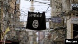 FILE - An Islamic State flag hangs amid electric wires, Jan. 19, 2016. 