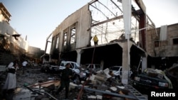 Orang-orang berdiri di lokasi serangan udara di sebuah gedung dimana acara berkabung atas meninggalnya ayah dari Mendagri Pemerintah Yemen yang didominasi kelompok Houthi dilaksanaka (8/10). (foto: REUTERS/Khaled Abdullah).