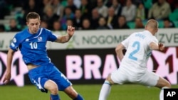 Gylfi Thor Sigurdsson, joueur de l’Islande, à gauche, aux prises avec Miso Brecko de la Slovénie lors d'un match de qualification de football du groupe E de la Coupe du Monde entre la Slovénie et l'Islande à Ljubljana, en Slovénie, 22 mars 2013. (AP Photo / Filip Horvat, File)