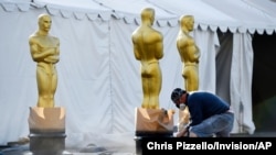 FILE - A scenic artists prepares Oscar statues off of Hollywood Boulevard for last years's 92nd Academy Awards, at the Dolby Theatre, Feb. 5, 2020, in Los Angeles, California.