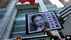 A placard with a photo of legal scholar Xu Zhiyong is raised by a demonstrator protesting against a Chinese court’s decision to sentence him in prison outside the Chinese liaison office in Hong Kong, Jan. 27, 2014.