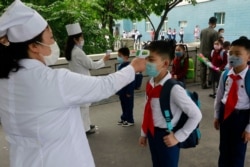 FILE - Kim Song Ju Primary School students have their temperatures checked in Pyongyang, North Korea, June 3, 2020. After months of denying it had any coronavirus infections, North Korea reported its first suspected case July 25, 2020.