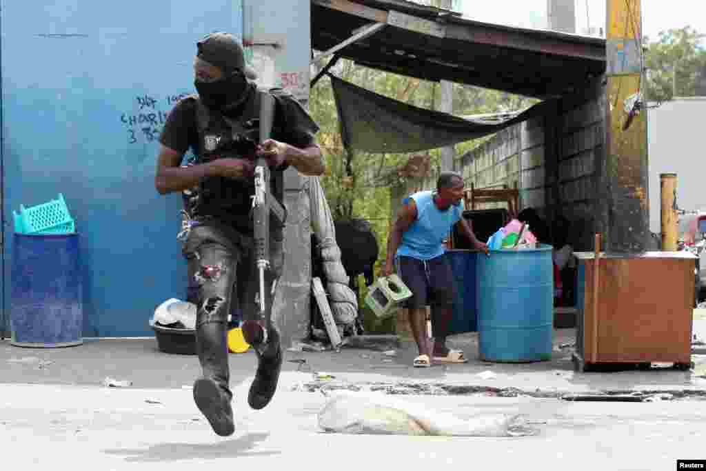 Seorang polisi berlari saat terjadi bentrokan dengan geng, sementara seorang warga lingkungan Delmas 30 melarikan diri dari rumahnya karena kekerasan geng, di Port-au-Prince, Haiti. (Reuters) 