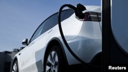 ລົດໄຟຟ້າຂອງບໍລິສັດ Tesla ກຳລັງສາກໄຟຟ້າຢູ່.