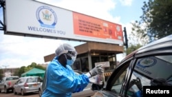 Mfanyakazi wa hospitali mjini Harare, Zimbabwe akichukua kipimo cha joto la dereva kabla ya kuingia ndani ya eneo la hospitali Machi 26, 2020. REUTERS/Philimon Bulawayo