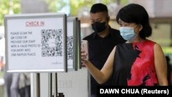 Pekerja kantor memindai kode QR Safe Entry untuk memasuki mal, di tengah wabah COVID-19 di Singapura 12 Mei 2021. (Foto: REUTERS/Dawn Chua)