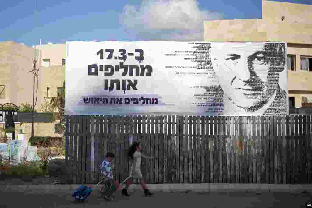 Anak-anak melewati spanduk kampanye pemilu bergambar Perdana Menteri Israel di Netanya, Israel (2/3). Israel akan mengadakan pemilihan umum pada 17 Maret dan Netanyahu berusaha mempertahankan jabatannya untuk periode keempat. (AP/Ariel Schalit)