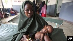A woman holds her malnourished child on arrival at Banadir hospital in Mogadishu, Somalia, July 7, 2011