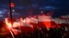 FILE - Demonstrators burn flares and wave Polish flags during an annual march to mark Poland's National Independence Day, in Warsaw, Poland, Nov. 11, 2017. 