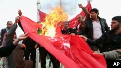 Demonstran membakar bendera Turki dalam sebuah protes menuntut penarikan pasukan Turki dari Irak utara, di Basra, Irak, 18 Desember 2015.