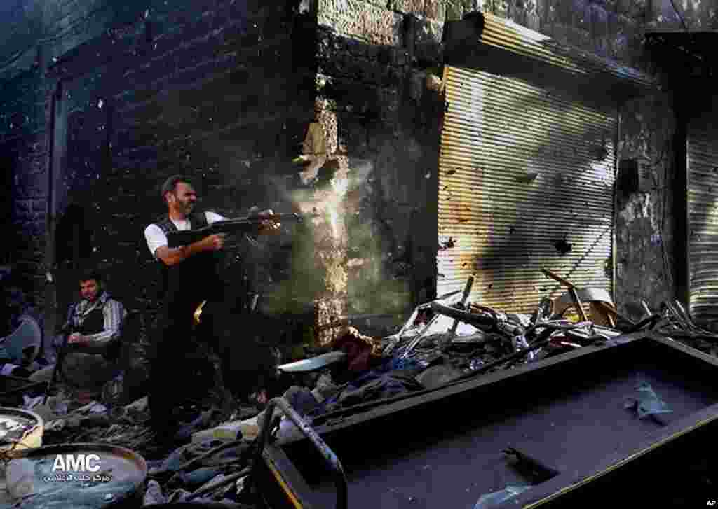 This citizen journalism image provided by Aleppo Media Center AMC shows a rebel firing his weapon during heavy clashes with soldiers in Aleppo, Syria, June 24, 2013.
