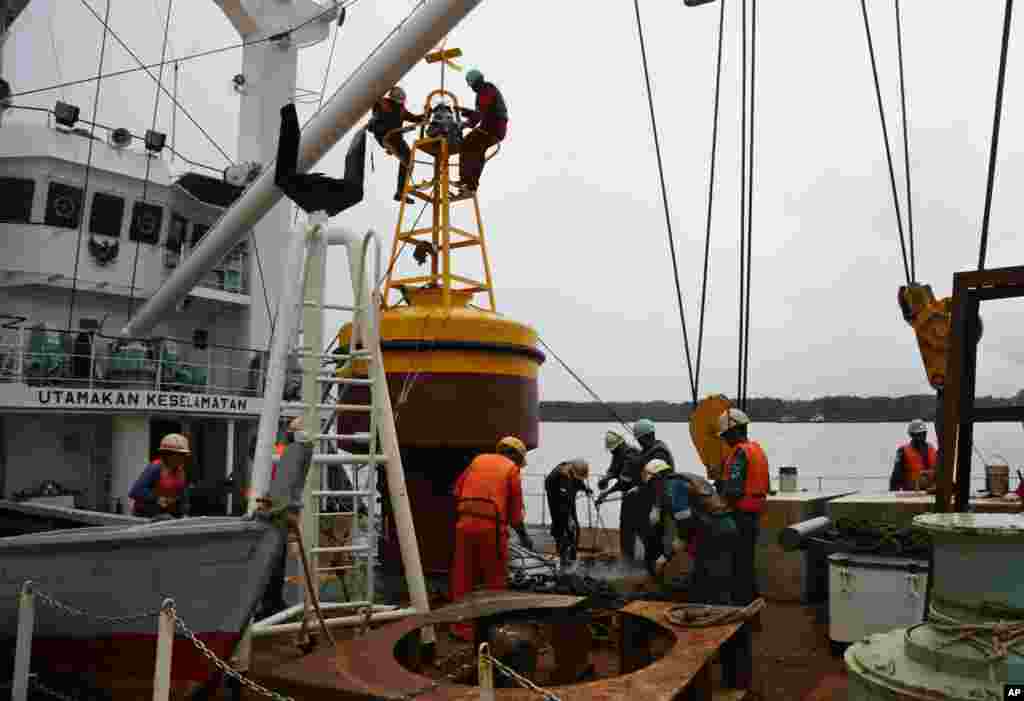 Para anggota kapal navigasi KN Jadayat mempersiapkan pelampung suar untuk memulai operasi pencarian bangkai pesawat AirAsia 8501 di Pelabuhan Kumai, Pangkalan Bun (5/1). (AP/Achmad Ibrahim)