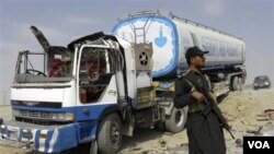 Pasukan keamanan Pakistan menjaga truk tangki bahan bakar NATO setelah terjadinya serangan oleh militan bersenjata.