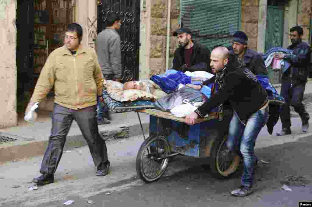 People wheel a sick man on a makeshift stretcher at the Karaj al-Hajez crossing, Aleppo, Feb. 9, 2014. 