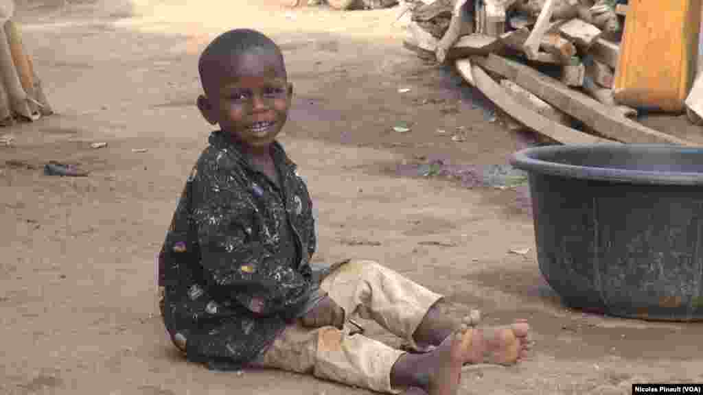 Wani Yaro A Zaune Yana Kallon Babaar Sa A Yayin Da Take Kokarin Dauraye Kayan Sawar Su A Sansanin Kuchogoro, Abuja Najeriya. 