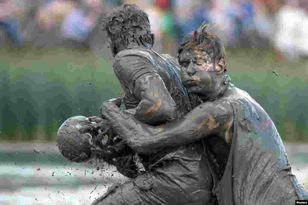 Participants fight for the ball during a handball match at the so called "Wattoluempiade" (Mud Olympics) in Brunsbuettel at the North Sea, Germany, July 30, 2016.