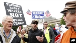 A supporter of Wisconsin Gov. Scott Walker, right, talks with a supporter of Democratic opponent Tom Barrett at a recall election rally June 1, 2012, in Milwaukee. 