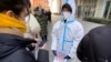 2022年1月26日(周三)，一名身穿防护服的工作人员手持印有“北京健康码”的二维码的纸，在北京一家私人冠状病毒检测中心进行检测。