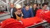 FILE PHOTO - Prime Minister Hun Sen, center, leans over a garment worker during a visit to a factory outside of Phnom Penh, Cambodia, Wednesday, Aug. 30, 2017. 