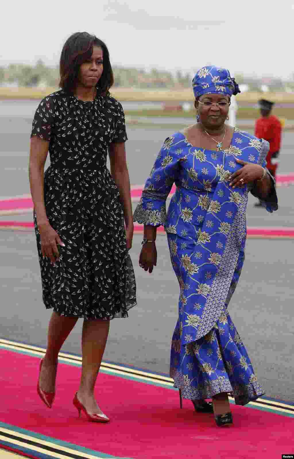 U.S. First lady Michelle Obama walks with Salma Kikwete, wife of Tanzania's president, during a departure ceremony in Dar es Salaam, July 2, 2013.