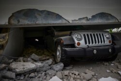 A car is crushed under a home that collapsed after the previous day's magnitude 6.4 earthquake in Yauco, Puerto Rico, Jan. 8, 2020. More than 250,000 Puerto Ricans remained without water and another half a million without electricity.