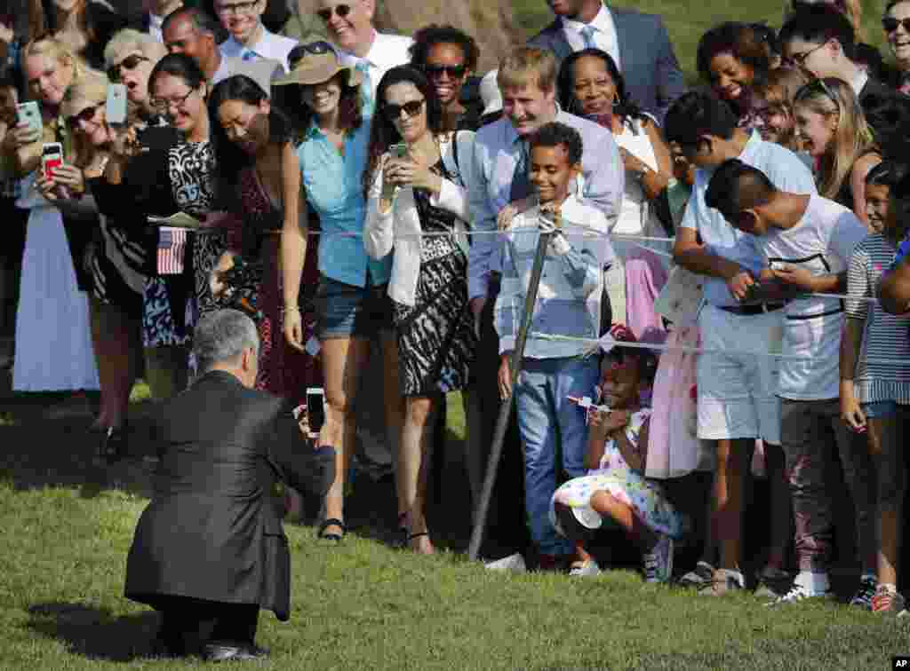 Singapore's Prime Minister Lee Hsien Loong uses his cell phone to photograph a young girl as other guests watch during a state arrival ceremony on the South Lawn of the White House in Washington.