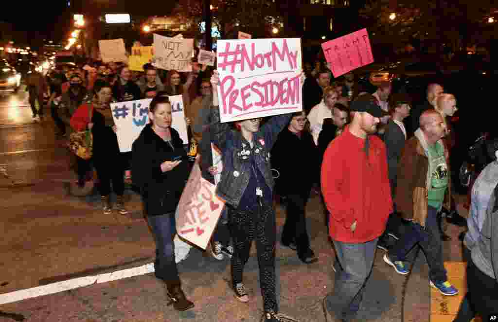 Para demonstran di Louisville, Kentucky, memegang papan bertuliskan tulisan yang menolak kemenangan Donald Trump pada pemilihan presiden (10/11). (AP Photo/Timothy D. Easley)