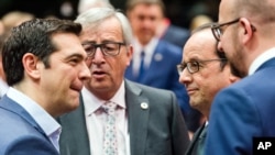 Greek Prime Minister Alexis Tsipras, left, speaks with, from left, European Commission President Jean-Claude Juncker, French President Francois Hollande and Belgian Prime Minister Charles Michel during a meeting of eurozone heads of state at the EU Council building in Brussels on Sunday, July 12, 2015. (AP Photo/Geert Vanden Wijngaert)