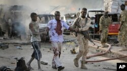 Seorang tentara Somalia menolong seorang warga sipil yang terluka dalam sebuah ledakan di Ibu Kota Mogadishu, 14 Oktober 2017. 